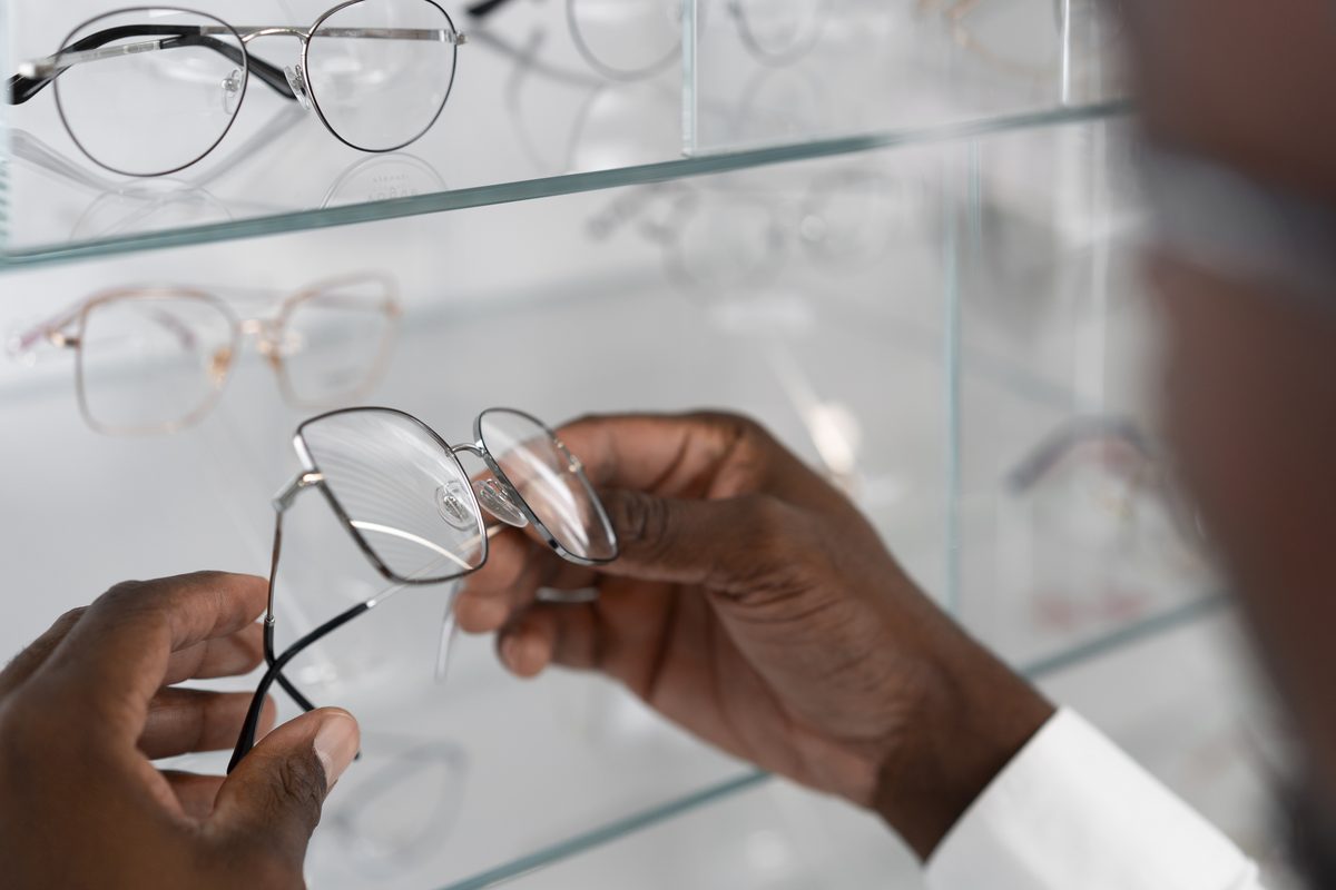 Hands choosing eyeglasses at a frame display case